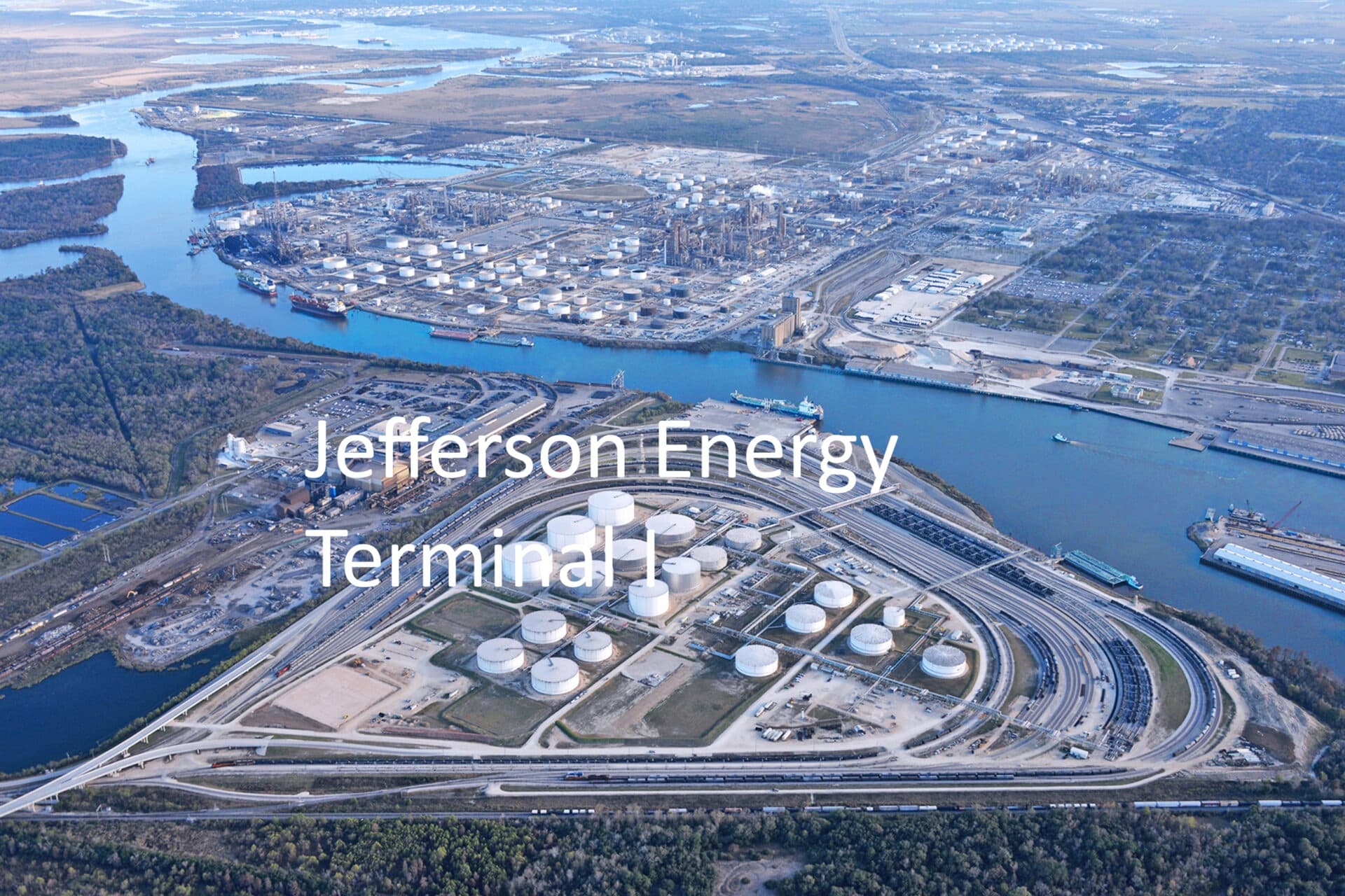 Aerial view of Jefferson Energy Terminal featuring storage tanks, rail tracks, and ships on water.